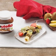 Brochette di crepe ripiene di Nutella e frutta, servite su stecco.