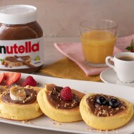 Pancake giapponesi alti serviti con Nutella e frutti di bosco.