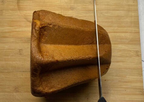 Un pandoro è stato posizionato su un lato. Un coltello è posizionato in alto per tagliare a circa 3-4 cm dall'altezza.