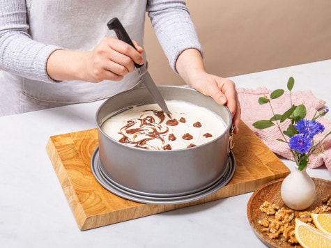 Usando un coltello il pasticciere crea piccoli vortici sopra la superficie della cheesecake senza cottura e Nutella® per una finitura decorativa.