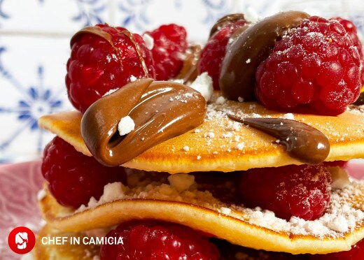 Pancake con Nutella, lamponi freschi e meringa, impilati e serviti.