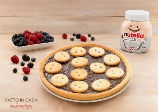 Crostata decorata a forma di sorriso, farcita con Nutella e frutta.