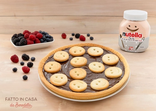 Crostata decorata a forma di sorriso, farcita con Nutella e frutta.