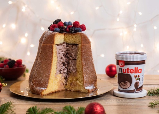 Un pandoro decorato con frutti di bosco è esposto su un piatto d'oro. È stato aperto per rivelare il ripieno di Nutella Gelato.