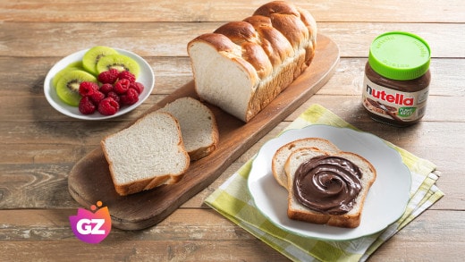 Fetta di crostata al cioccolato con striature di Nutella e nocciole.