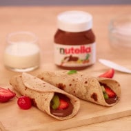 Warm roti folded and generously spread with Nutella on plate.