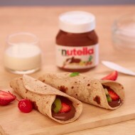 Warm roti folded and generously spread with Nutella on plate.