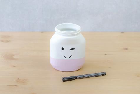 Upcycled Nutella jar painted with smiling face craft, step four.