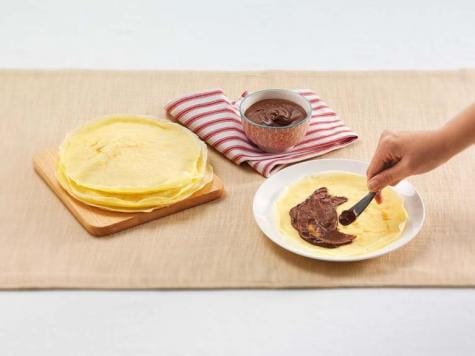 Folding Nutella-filled crepes and arranging fruit garnish, recipe step two.