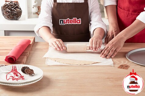 Assembling shortbread sandwiches by spreading Nutella between cookie layers.
