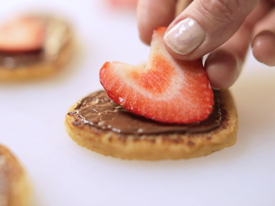 Paso de receta: galletas en forma de corazón rellenas y decoradas.