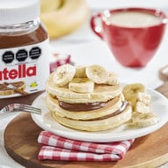 Panqueques con Nutella y rodajas de plátano, servidos con miel.