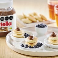 Panqueques con Nutella y mezcla de frutos rojos, coronados con crema.