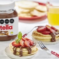 Panqueques con Nutella y fresas frescas, servidos con jarabe.