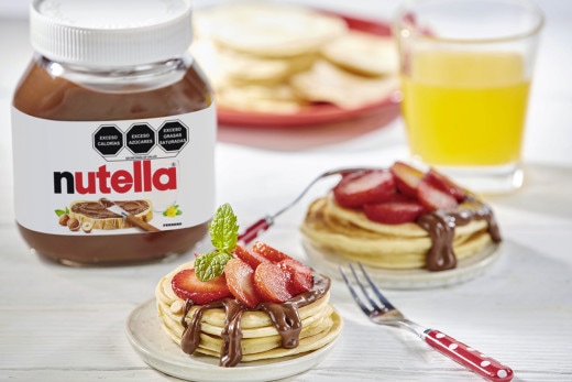 Panqueques con Nutella y fresas frescas, servidos con jarabe.