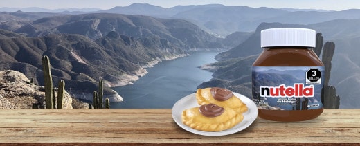 Escena doméstica Nutella: desayuno con tostadas, fruta y vajilla tradicional.