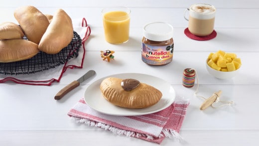 Empanadas de coco doradas con relleno cremoso, servidas en plato blanco.