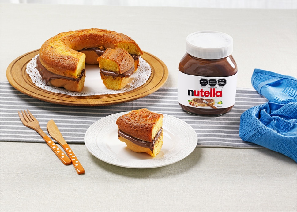 Ciambella esponjosa con glaseado de Nutella, decorada con azúcar glas.