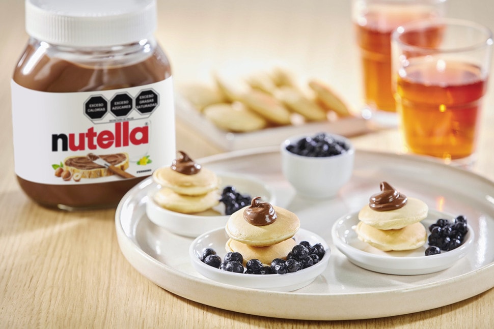 Panqueques con Nutella y mezcla de frutos rojos, coronados con crema.
