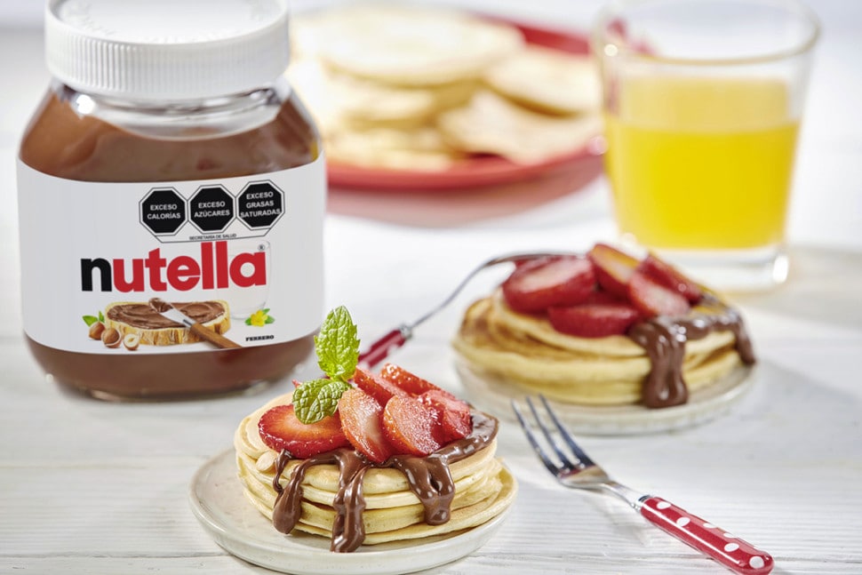 Panqueques con Nutella y fresas frescas, servidos con jarabe.