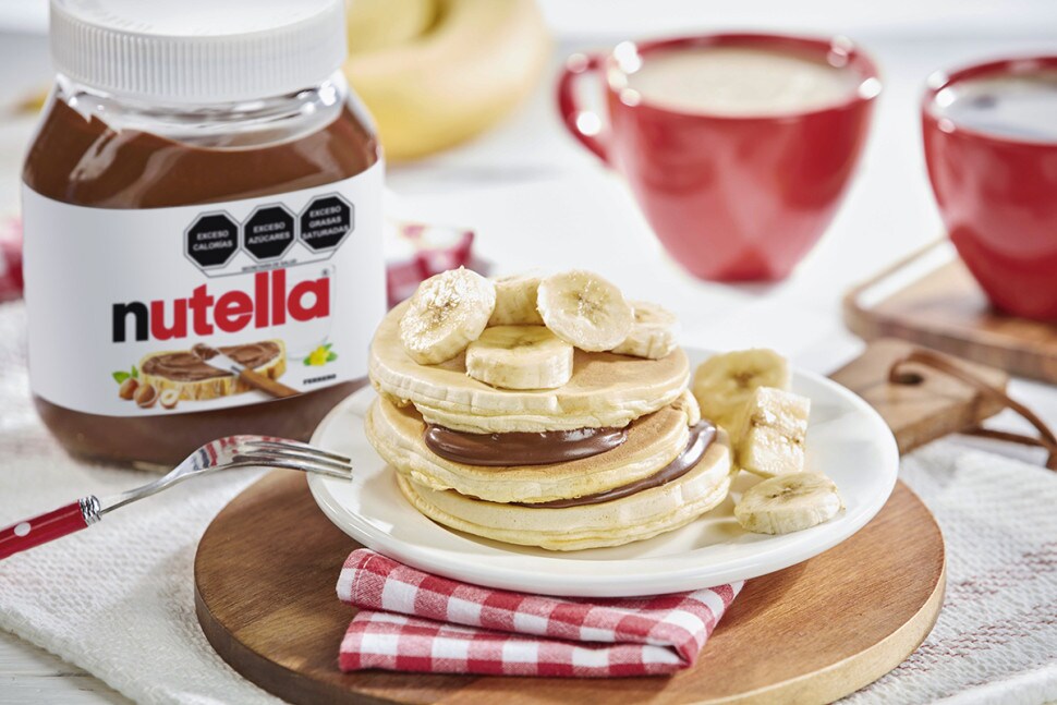 Panqueques con Nutella y rodajas de plátano, servidos con miel.