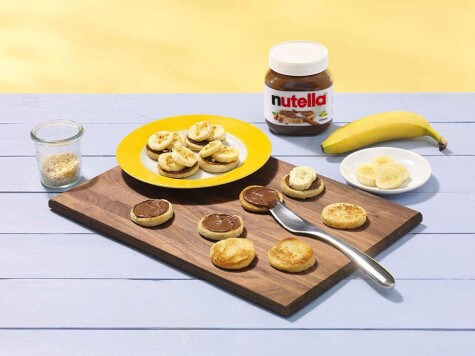 Smarowanie chlebowych ciasteczek kremem Nutella® i dekorowanie bananami