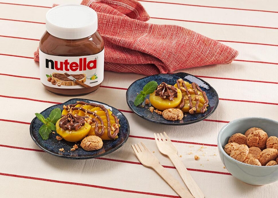 Brzoskwinie z ciasteczkami Amaretti i kremem Nutella® podane na granatowych talerzykach