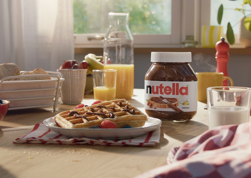 Golden waffles stacked, drizzled with Nutella and topped with berries.