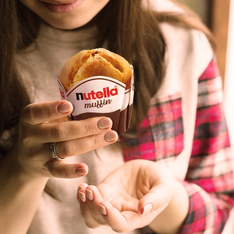Nutella muffin topped with creamy chocolate-hazelnut filling on white plate.
