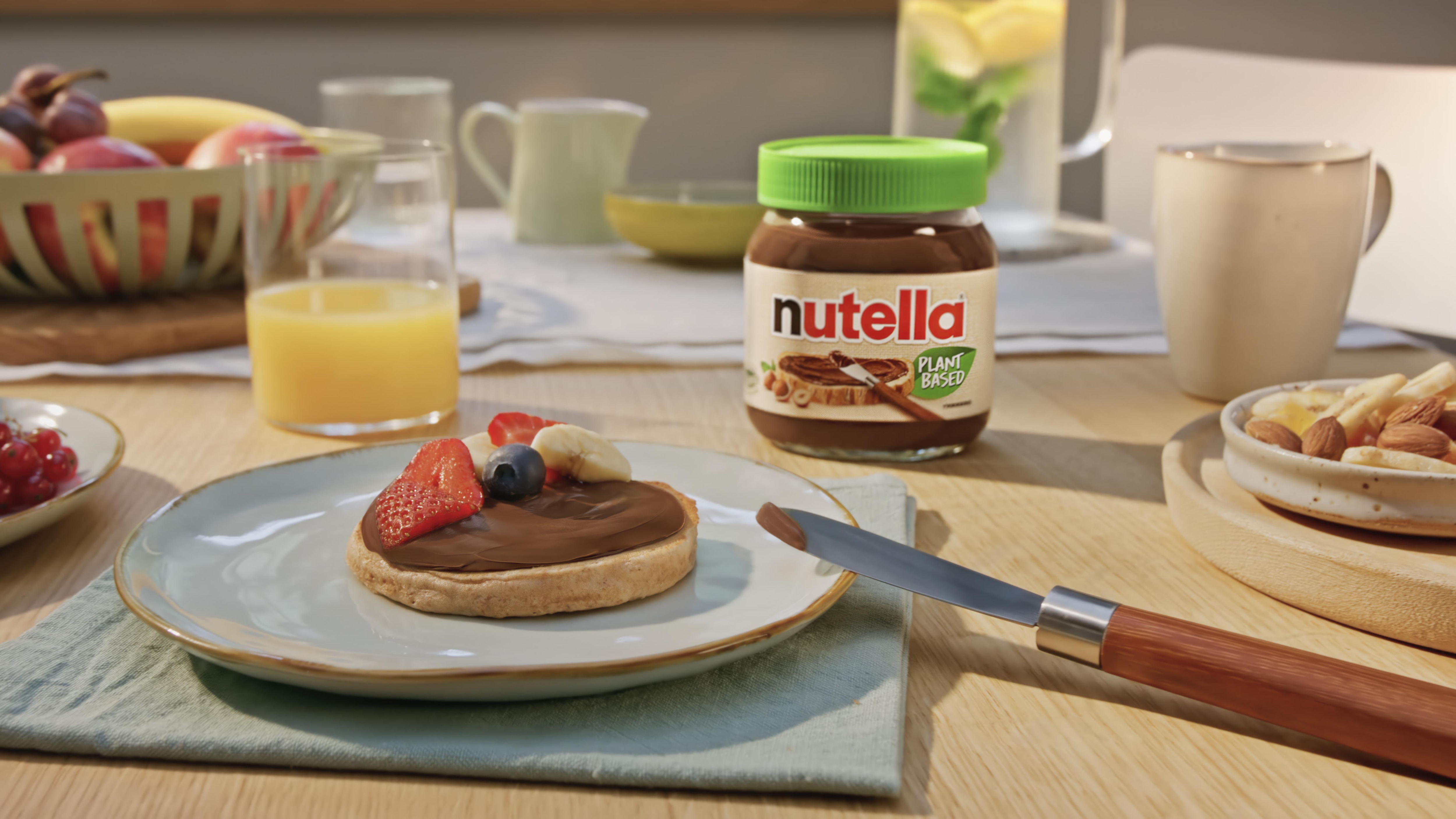Frontal view of vegan pancakes topped with Nutella plant-based spread and syrup.