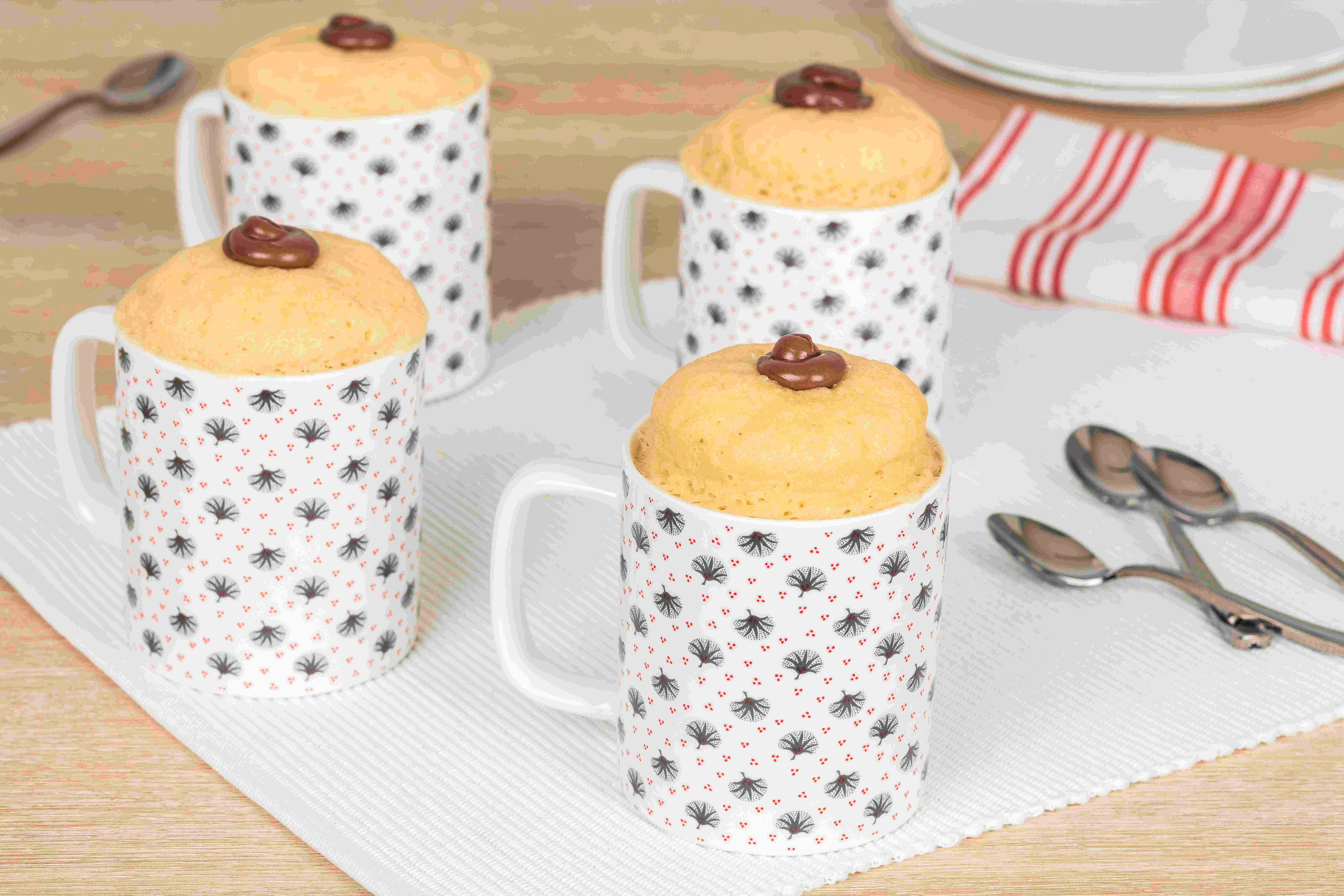 Individual mug cake topped with Nutella and chocolate shavings, served warm.