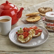 Toasted breakfast bagel spread with Nutella and fresh berries.