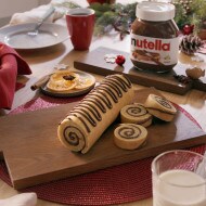 Nutella yule log with chocolate ganache and cream decoration.