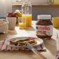 Plate of crepes drizzled with Nutella and sprinkled with chopped hazelnuts.