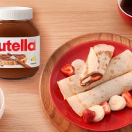 Vegan crepes spread with Nutella plant-based, rolled and garnished with berries.
