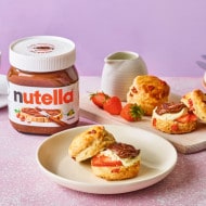 Delicious breakfast scones with strawberries, whipped clotted cream, and Nutella®, served with tea and coffee.