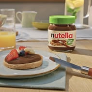 Frontal view of vegan pancakes topped with Nutella plant-based spread and syrup.