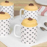 Individual mug cake topped with Nutella and chocolate shavings, served warm.