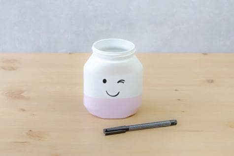 Step 2: painting facial features on Nutella jar for smiling jar craft.