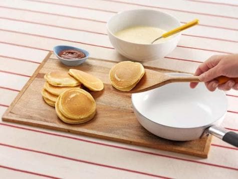 Step three: topping cooked mini pancakes with Nutella and sliced fruit.