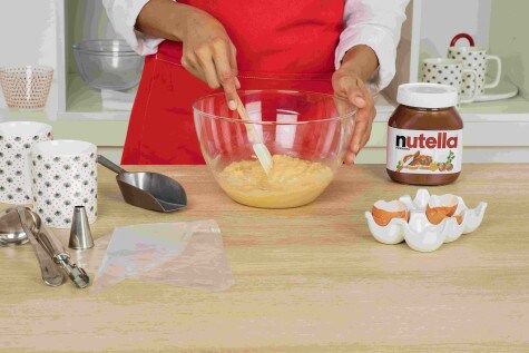 A baker is mixing the mug cake ingredients in a glass mixing bowl using a silicone spatula.