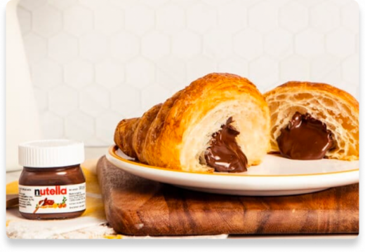 Mini Nutella jar served beside a golden brioche pastry on plate.