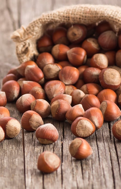 Bag of hazelnuts spilling onto surface, key ingredient for Nutella spread.