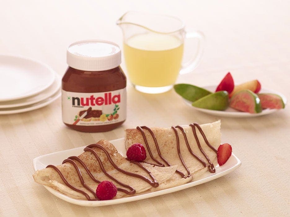 Crispy dosa rolled and filled with Nutella, served with sliced fruit.