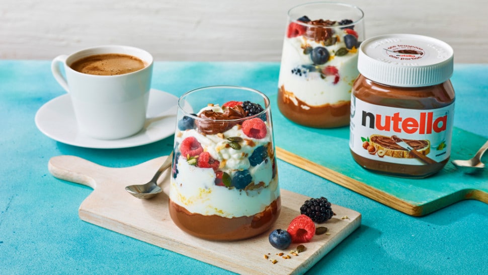 Mixed berry and nut yoghurt parfait with Nutella®, served in glasses with fresh fruit and a Nutella® jar.