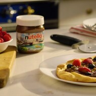 Breakfast pizza topped with Nutella, banana slices and fresh berries