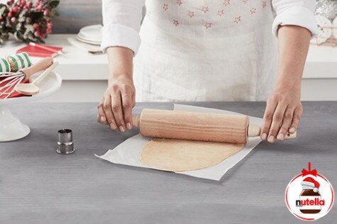 A baker rolls out the craquelin dough onto parchment paper.