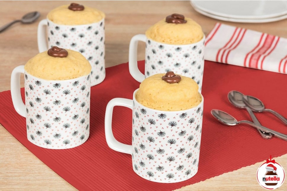 Four mug cakes in are displayed on a red place mat with a dollop of Nutella® in the centre of the cake.