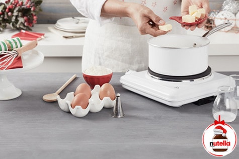 A baker prepares the choux pastries by placing butter into a pot.