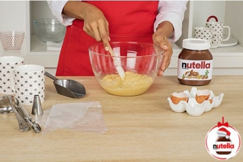 A baker is mixing the mug cake ingredients in a glass mixing bowl using a silicone spatula.